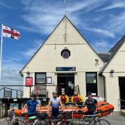 Cyclist Harry Lidgley, centre, with two friends, George Hayes and Oli Dawe-Lane, and members of the Calshot RNLI crew. Picture: Calshot RNLI.
