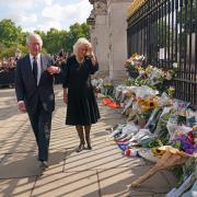King Charles III and the Queen view tributes left outside Buckingham Palace, London, following the death of Queen Elizabeth II on Thursday. PA.