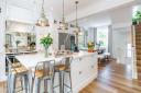 Bar stools with an industrial aesthetic, copper pendants and rustic refectory table add character to the sociable kitchen-dining room