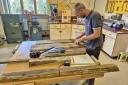 Multiply learner Jamie Walker with a coffee table he built in a Practical Woodworking and Numeracy Skills course