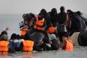 People thought to be migrants wade through the sea to board a small boat leaving the beach at Gravelines, France, in an attempt to reach the UK by crossing the English Channel (Gareth Fuller/PA)
