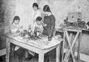 Women's Emergency Corps. Under the headline “Not Made In Germany” the pictures show the interior of the workroom of the Women’s Emergency Corps premises at Hanover Buildings as a party of keen workers are busily engaged in making toys of all