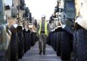 A member of the Royal Logistic Corps inspects a row of Foxhound patrol vehicles ahead of them being loaded onto sealift ship, MV Hurst Point, at The Sea Mounting Centre in Marchwood