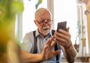 A stock image of an elderly man on his phone