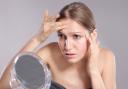 Woman pauses at mirror during flare-up, reflecting silent skin struggles