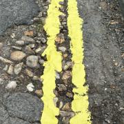 Council workers have come under fire after painting double yellow lines through the centre of potholes