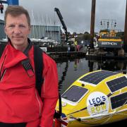 Russian consultant anaesthetist Leo Krivskiy standing in front of his row boat, Happy Socks.