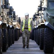 A member of the Royal Logistic Corps inspects a row of Foxhound patrol vehicles ahead of them being loaded onto sealift ship, MV Hurst Point, at The Sea Mounting Centre in Marchwood