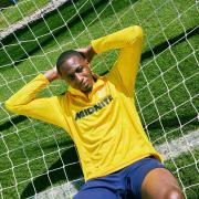 Joe Aribo models a new yellow training fleece with sponsor Midnite across the torso