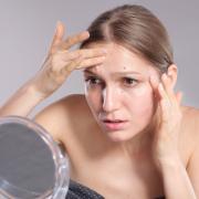 Woman pauses at mirror during flare-up, reflecting silent skin struggles