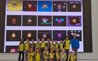 The Brownie pack in front of the large screen at the Apple store showcasing their emoji designs