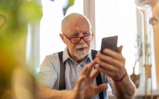 A stock image of an elderly man on his phone